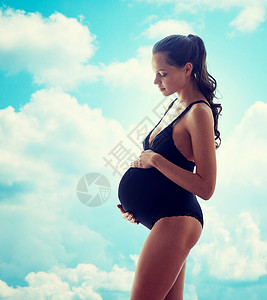 怀孕,母亲,人期望的快乐的孕妇穿着黑色内衣蓝天云彩的背景下图片