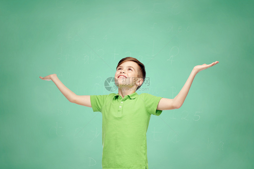 童,成就,快乐人的快乐的微笑男孩绿色马球T恤举手仰望绿色学校粉笔板背景图片