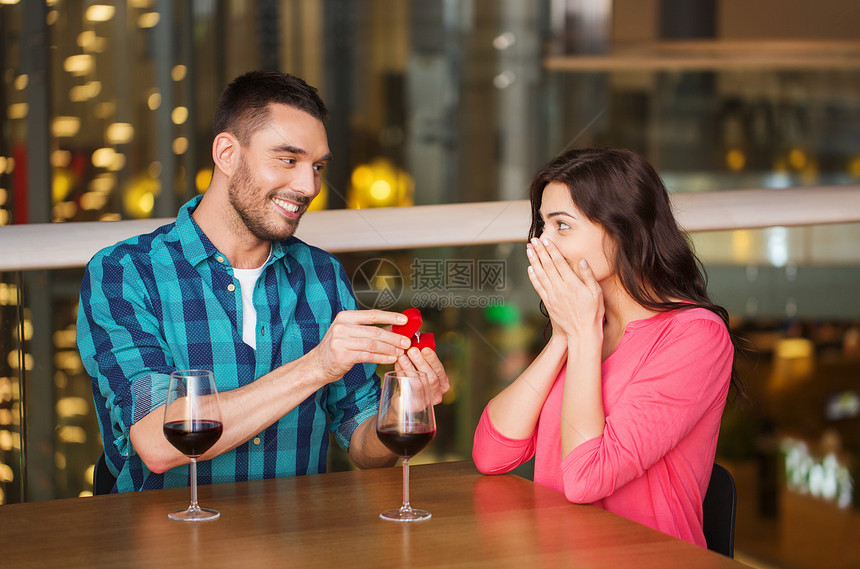 人,求婚,爱情,夫妻假期的微笑的男人给他餐馆快乐的女朋友钻石订婚戒指图片