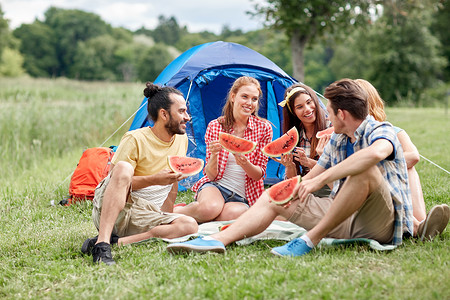 旅行,旅游,远足,野餐人们的群快乐的朋友露营时吃西瓜图片