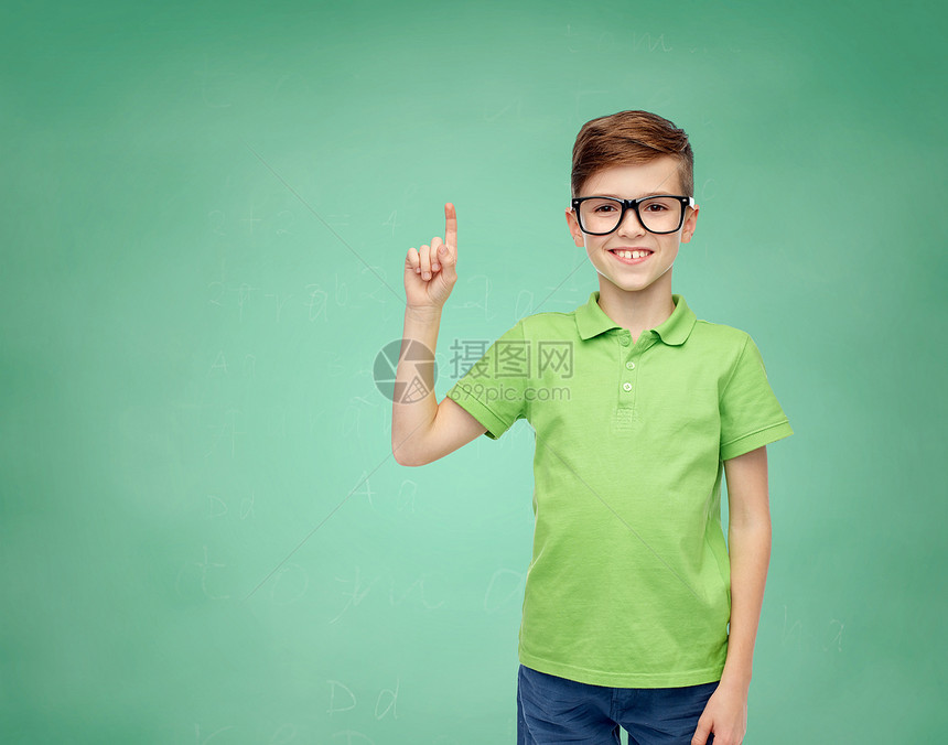 童,视觉,学校,教育人的快乐的微笑男孩穿着绿色马球T恤,戴着眼镜,手指指向绿色学校粉笔板的背景图片
