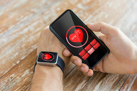 商业,技术,医疗人的近距离的男手着智能手机穿着智能手表红色心跳图标屏幕上图片