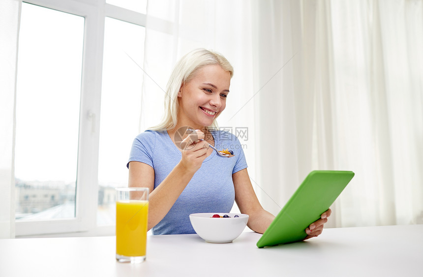 健康饮食,饮食,技术人的微笑的轻妇女与平板电脑电脑家里吃早餐图片