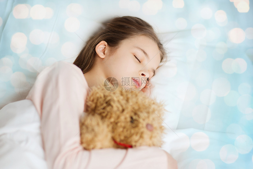 人,童,休息舒适的女孩睡蓝色灯光背景的床上泰迪熊玩具图片