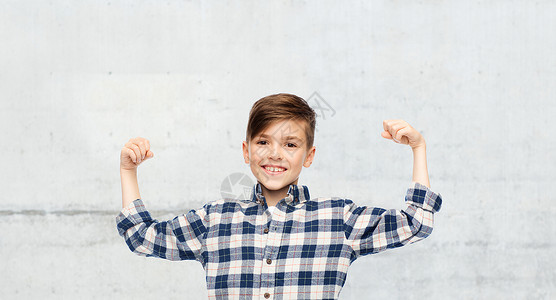童,权力,力量人的快乐的微笑男孩穿着格子衬衫,城市街道背景上出强大的拳头图片