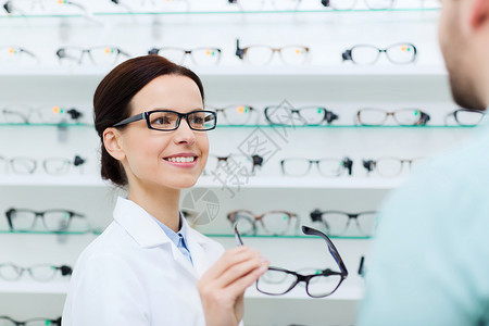 保健,人,视力视力女光学师光学商店向男展示眼镜图片