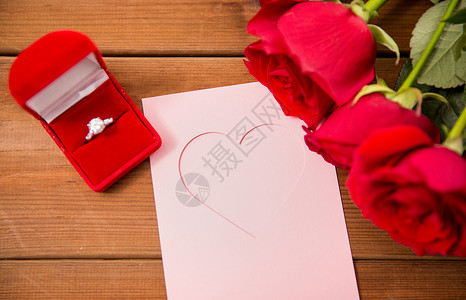 爱情,求婚,情人节假期的礼品盒与钻石订婚戒指,红色玫瑰贺卡木材上图片