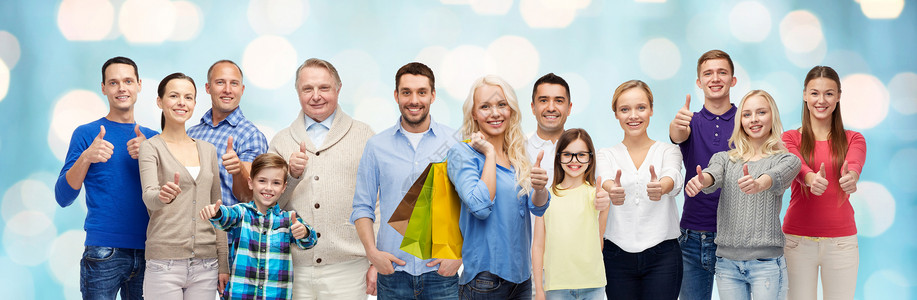 手势,销售人的群微笑的男人,女人孩子展示竖大拇指,着购物袋蓝色假日灯光背景图片