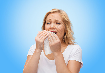 人,保健,鼻炎,感冒过敏的快乐的女人用纸巾打喷嚏的蓝色背景图片