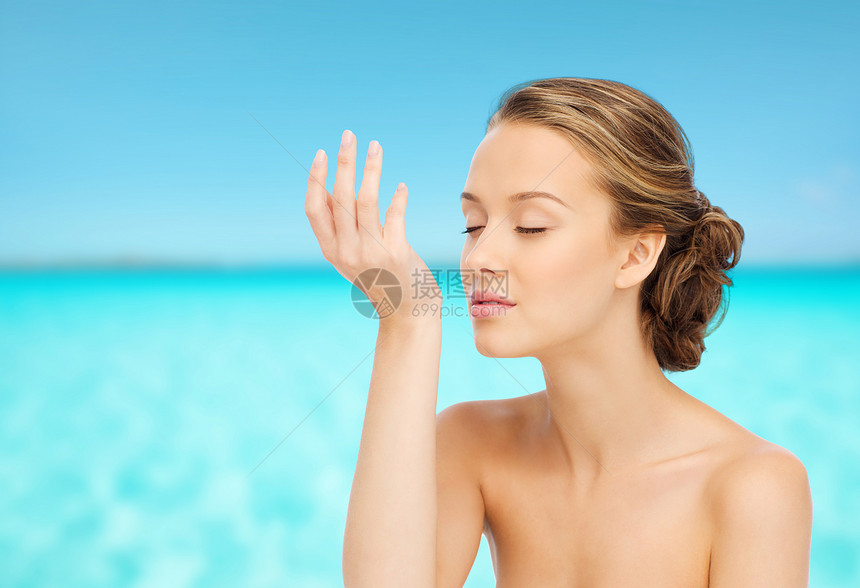 美丽,香气,人身体护理的轻的女人闻香水她的手腕蓝色的海洋天空背景图片