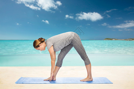 健身,运动,人健康的生活方式妇女瑜伽强烈伸展姿势垫子上的海滩背景图片