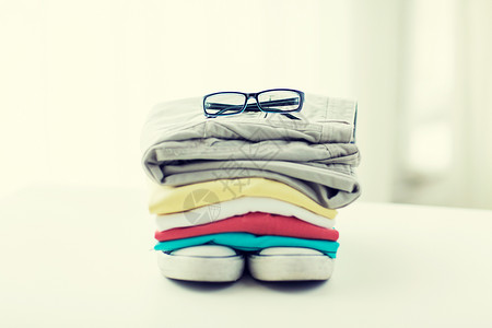 衣服,个人工作人员物品的折叠衬衫,裤子,眼镜鞋子家里的桌子上图片