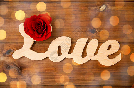 爱情,约会,浪漫,情人节假期的文字爱情剪断与红色玫瑰木材上的金色灯光背景图片