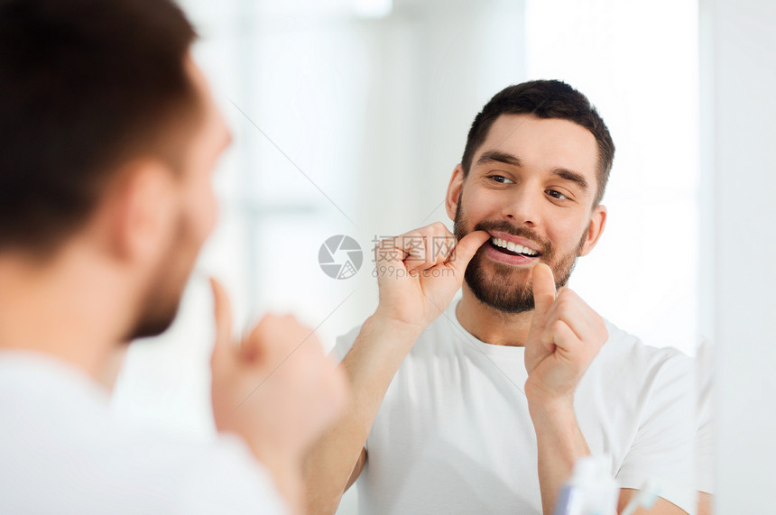 保健,牙科卫生,人美容微笑的轻人用牙线清洁牙齿,并家里的浴室照镜子图片