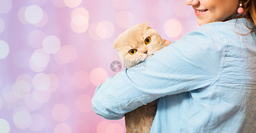 宠物,动物,护理人的亲密的快乐女人抱着苏格兰折叠小猫粉红色的节日灯光背景图片