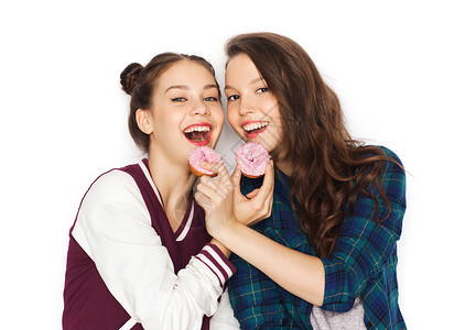 吃甜甜圈的女孩人,朋友,青少友谊的快乐的微笑漂亮的十几岁的女孩与甜甜圈吃玩背景
