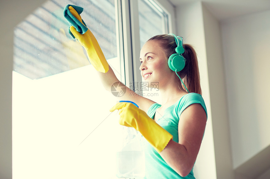 人,家务家务快乐的女人耳机听音乐清洁窗口与清洁剂家里图片