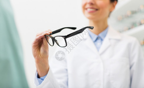 医疗保健,人,视力视力近距离微笑的女光学师持眼镜光学商店图片