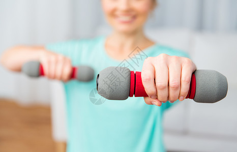 健身,运动,人健康的生活方式微笑的女人家里用哑铃锻炼图片