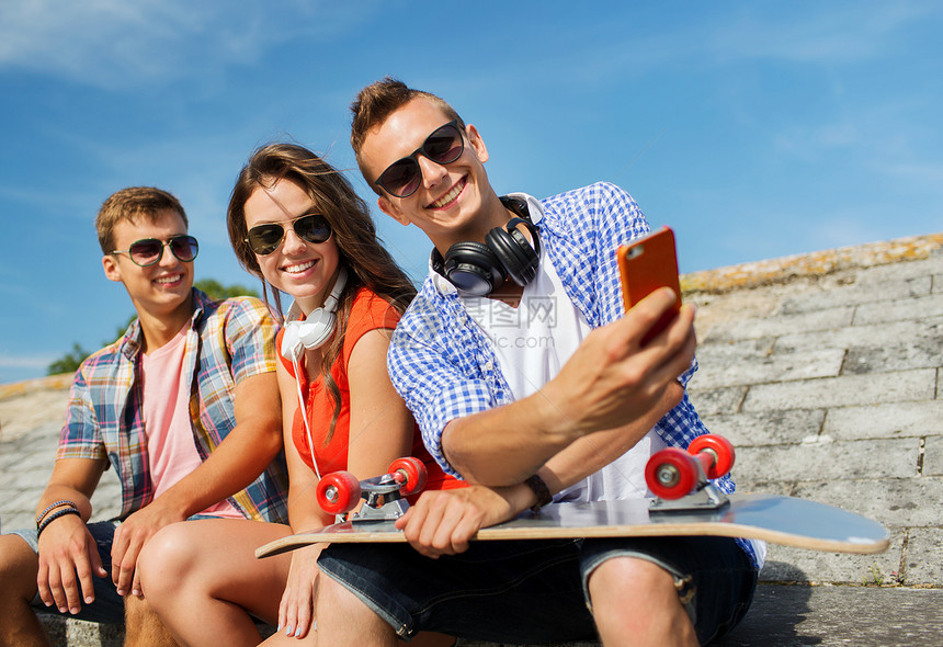 友谊,休闲,夏天,技术人的群微笑的朋友与滑板智能手机户外自拍图片