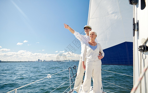 水手结航海,龄,旅游,旅行人们的快乐的老夫妇指着漂浮海上的帆船游艇甲板上的东西背景