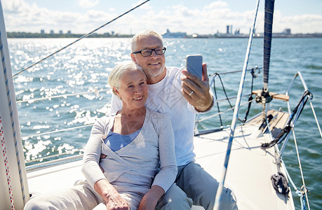 航海,技术,旅游,旅游人的快乐的老夫妇与智能手机自拍帆船游艇甲板漂浮海上图片