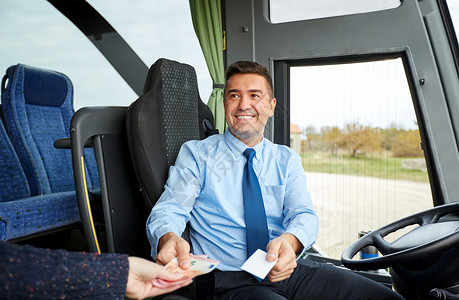 运输,旅游,公路旅行人的微笑的公共汽车司机卖票乘客那里钱图片
