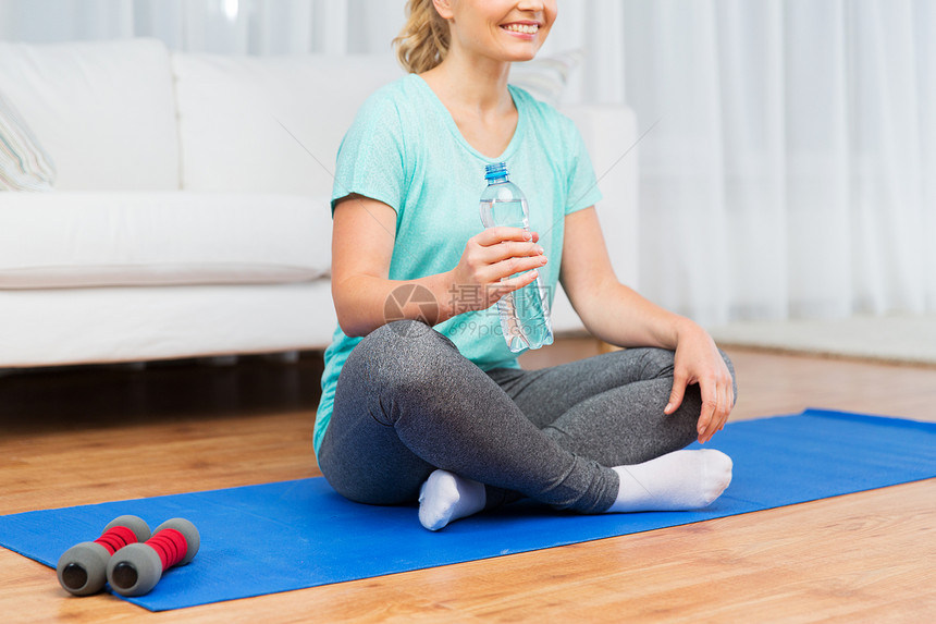 健身,运动,人健康的生活方式快乐的女人与瓶水后,家里的垫子上锻炼图片