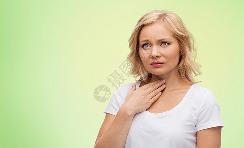 绿色T恤人,医疗保健问题快乐的女人触摸她的脖子喉咙疼痛的绿色自然背景背景