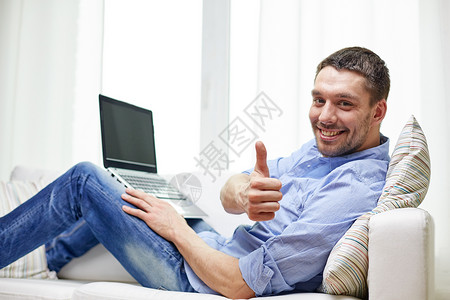 技术,人生活方式的微笑的人家里用笔记本电脑工作图片
