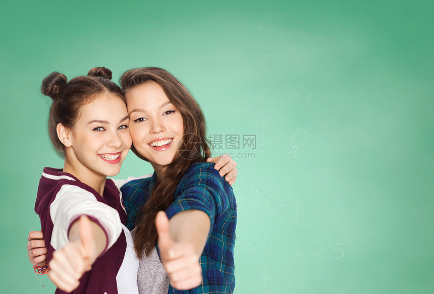 人,学校,教育,手势朋友的快乐的微笑,漂亮的十几岁的学生女孩拥抱展示拇指绿色粉笔板背景图片