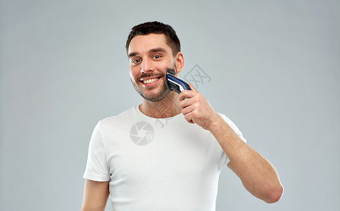 美丽,修饰人们的微笑的轻人刮胡子与修剪电动剃须刀灰色背景背景图片