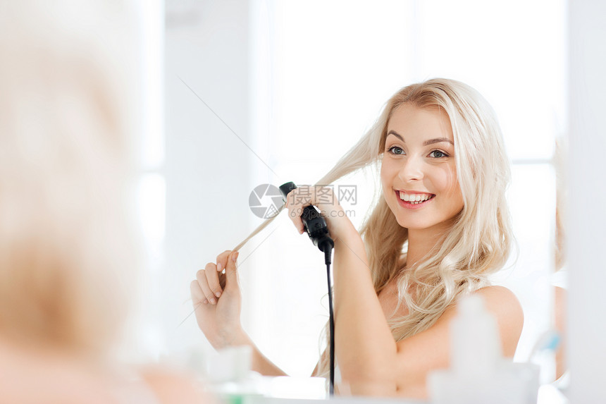 美丽,发型,早晨人的微笑的轻女人与造型铁拉直她的头发镜子家里的浴室图片