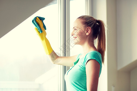 人,家务家务快乐的女人戴着手套,家用抹布擦窗户图片