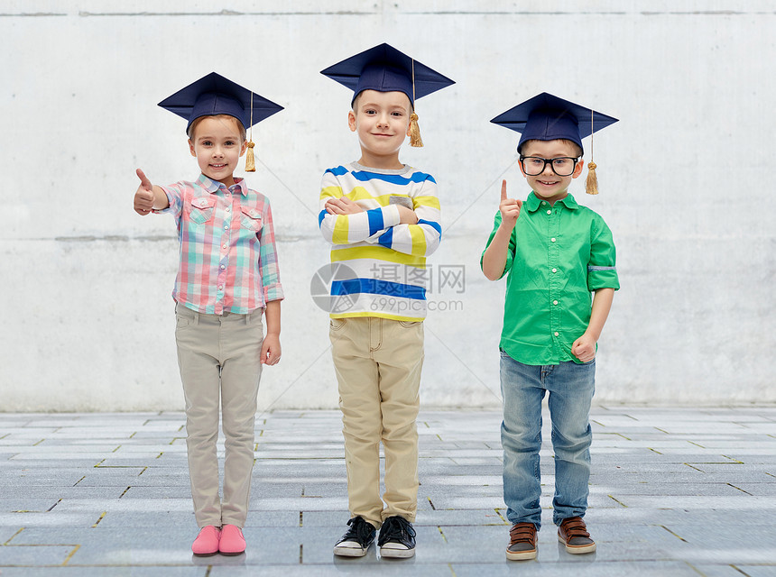 童学校教育知识人的城市混凝土背景下戴着学士帽沙浆板眼镜的快乐孩子图片