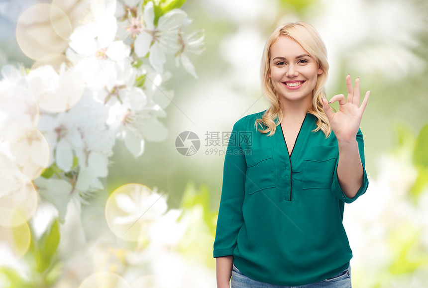 春天,手势,加上大小人的微笑的轻女人穿着衬衫牛仔裤,自然樱花背景上OK手标志图片