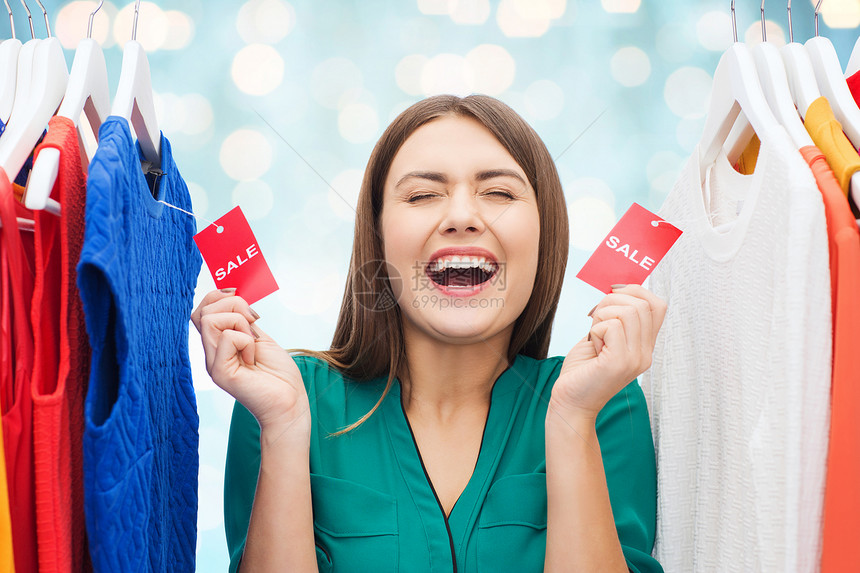 服装,时尚,销售,购物人们的快乐的女人蓝色假日灯光背景的衣柜里展示衣服上的标签图片