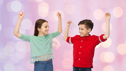 童,时尚,手势人的快乐的微笑男孩女孩举拳头,庆祝胜利的粉红色假日灯光背景图片