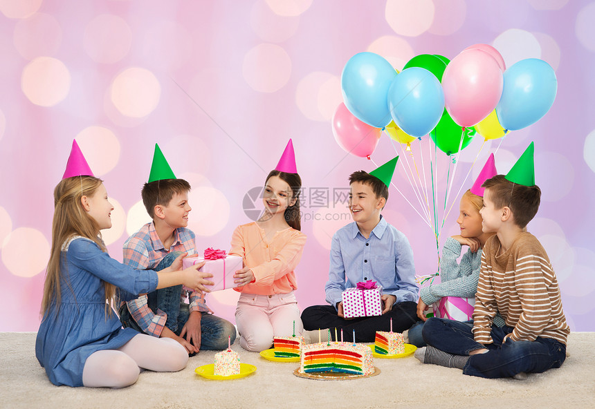 童,假期,庆祝,友谊人的快乐的微笑孩子戴着派帽,粉红色节日灯光背景下的生日聚会上送礼物图片