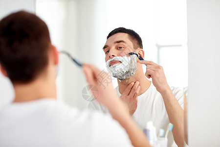 美容,卫生,剃须,美容人的轻人看镜子剃须胡须与手动剃须刀刀片家里浴室图片
