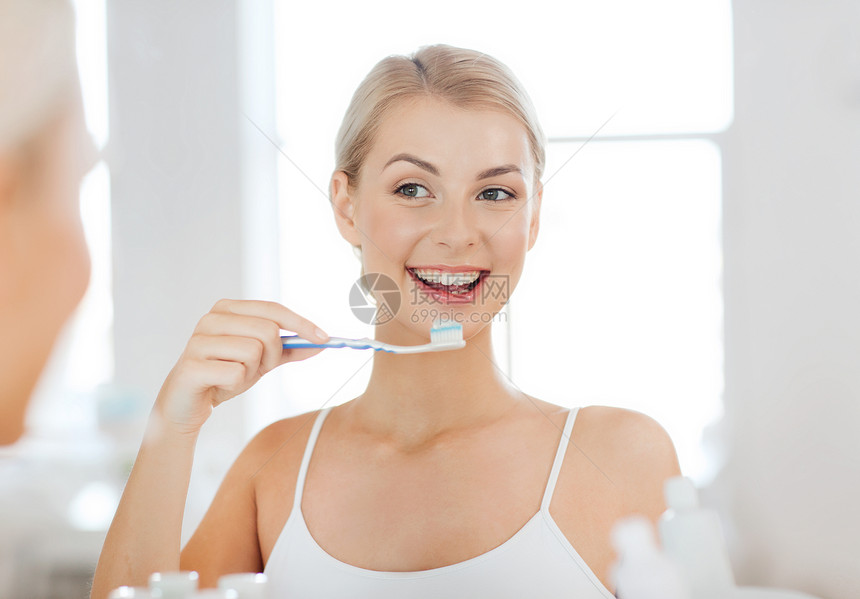 保健,牙科卫生,人与美的微笑的轻妇女牙刷,清洁牙齿,并家里的浴室看镜子图片