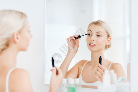 美丽,化妆,化妆品,早晨人的微笑的轻女人用睫毛膏化妆,家里的浴室照镜子图片
