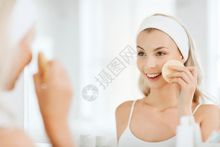 美容,皮肤护理人的微笑的轻洗她的脸与部清洁海绵浴室图片
