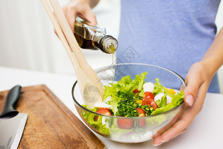 健康饮食,素食,饮食人们的密切轻妇女家里用橄榄油调味蔬菜沙拉图片