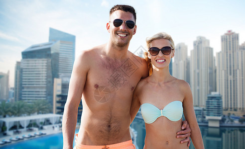 爱情,旅行,旅游,夏天人的微笑的夫妇度假泳装太阳镜拥抱迪拜城市海滨背景图片
