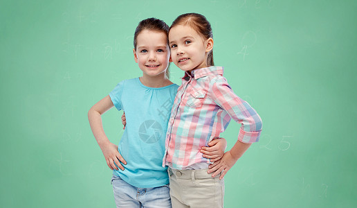 童,时尚,友谊人的快乐的微笑小女孩拥抱绿色学校粉笔板背景图片