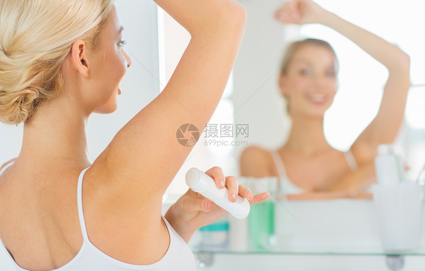 美容,卫生,早晨人的微笑的轻妇女应用止汗剂贴除臭剂,并家里的浴室看镜子图片