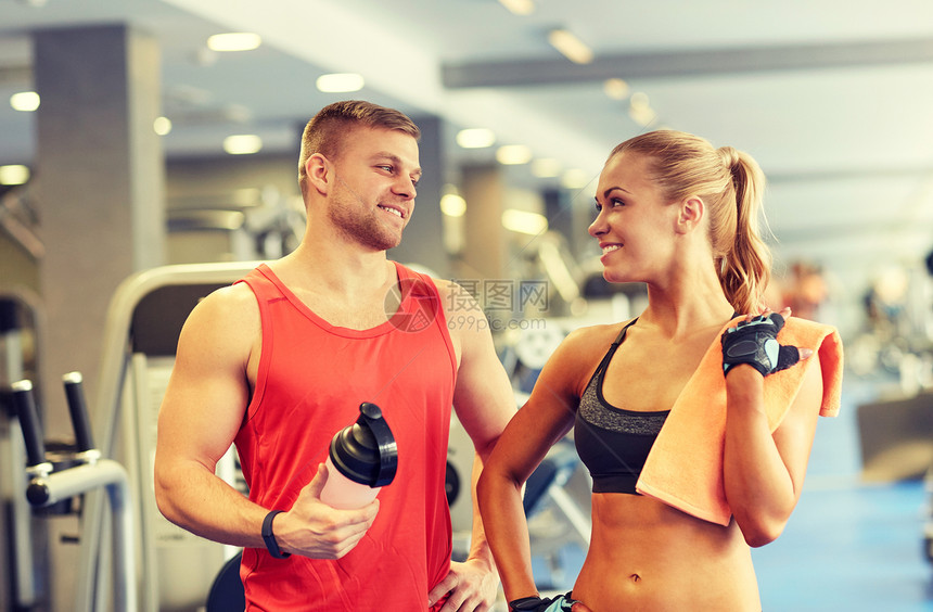 运动,健身,生活方式人们的微笑的男人女人与蛋白质瓶毛巾健身房交谈图片