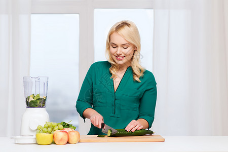 健康的饮食,烹饪,素食,饮食人的微笑的轻妇女与搅拌机刀切水果蔬菜切割板家里图片
