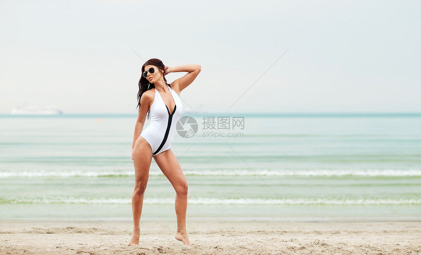 暑假,旅游,假期人的轻的女人穿着泳衣海滩上摆姿势图片